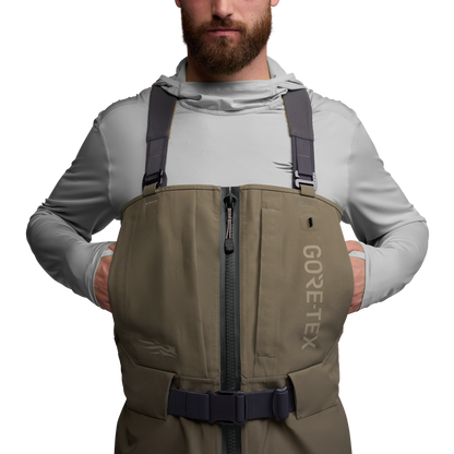 Man wearing a brown GORE-TEX vest over a light gray shirt on a white background