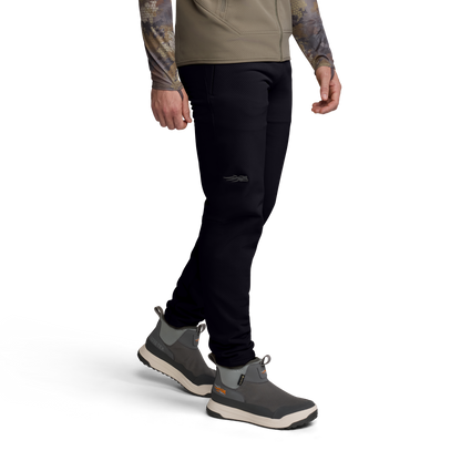 Person wearing black pants and gray shoes on a white background