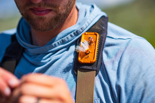 Cling Mag Grab Double Stack in orange attached to a fly angler’s shoulder strap, holding several flies securely for quick access on the water.