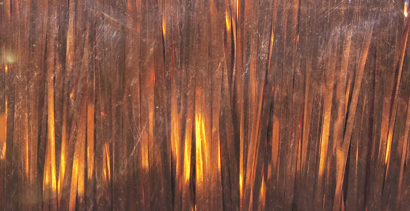 Close-up of Hareline Flashabou Magnum in copper showing wide, reflective strands with a metallic finish for fly tying.